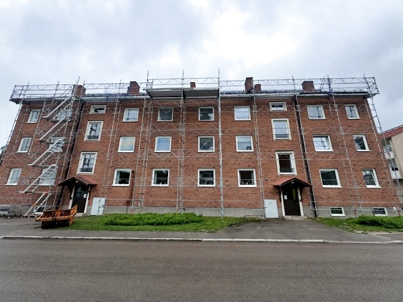 Fasadställning av typ +8 med trapptorn och skyddsräcken runt ett flerbostadshus under fasadrenovering